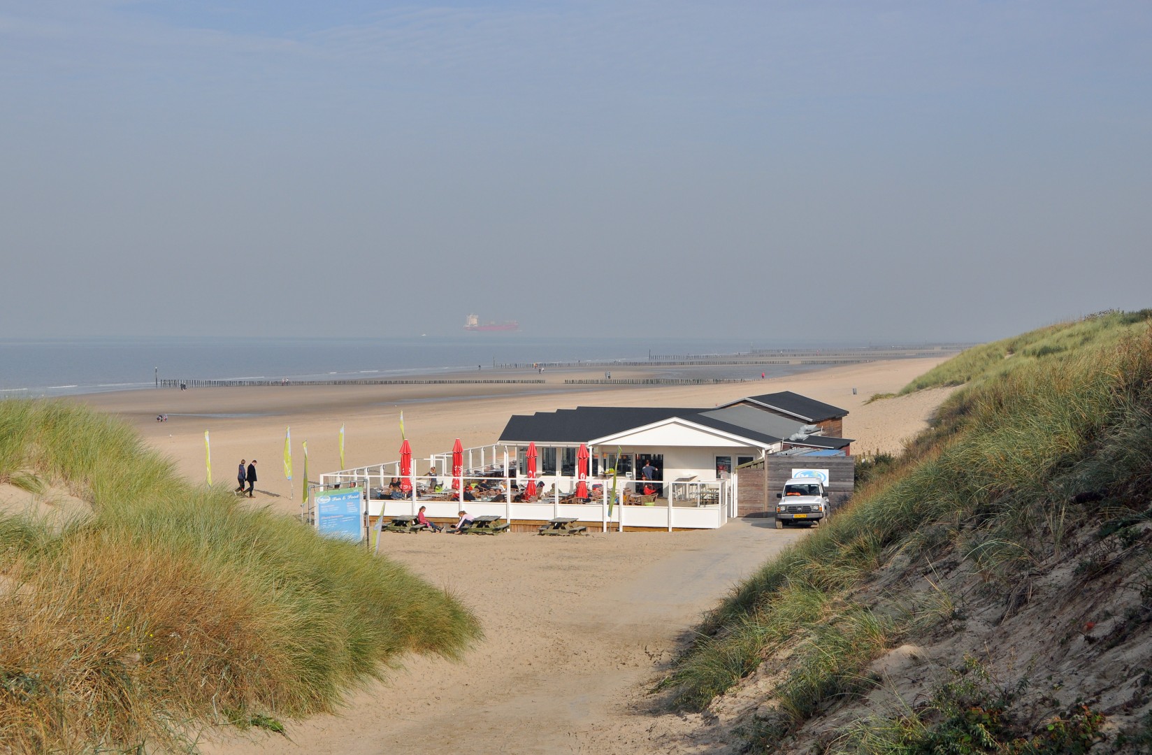Zandstrand van Cadzand-Bad met duinen, paalhoofden en strandpaviljoen